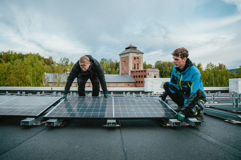 To stykker som monterer solcelleanlegg på flatt tak