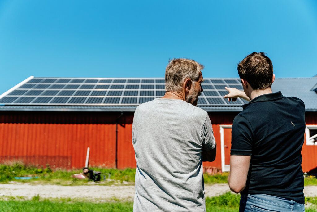 To menn ser på solcelleanlegg på fjøstak