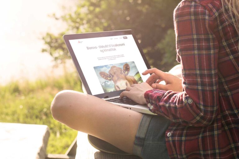 Dame som sitter med laptop på fanget med nettsiden til Innovasjon Norge/Bionova oppe for å se på tilskuddsordninger til landbruket
